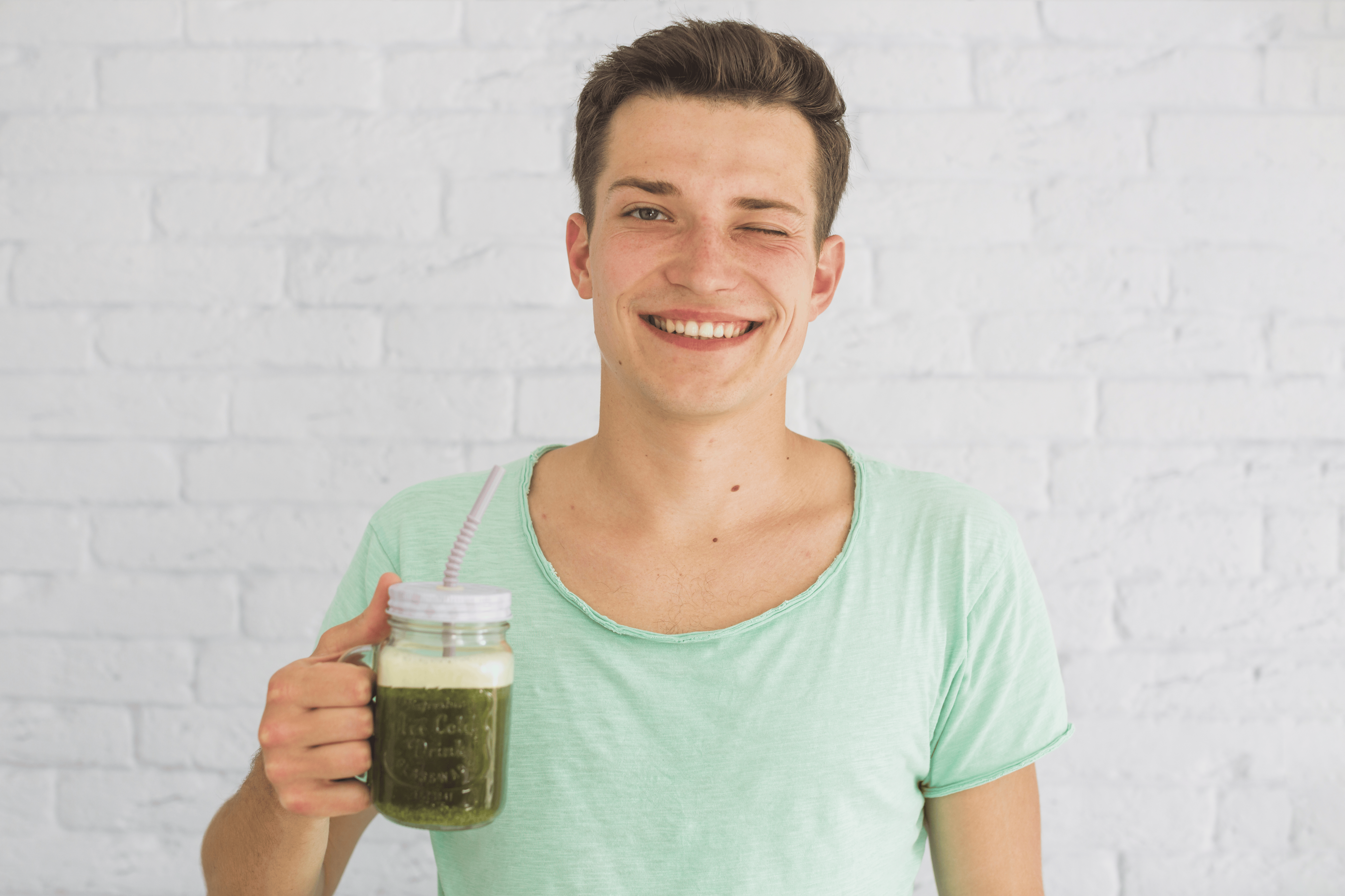 happy-man-holding-blended-green-smoothies-jar-winking