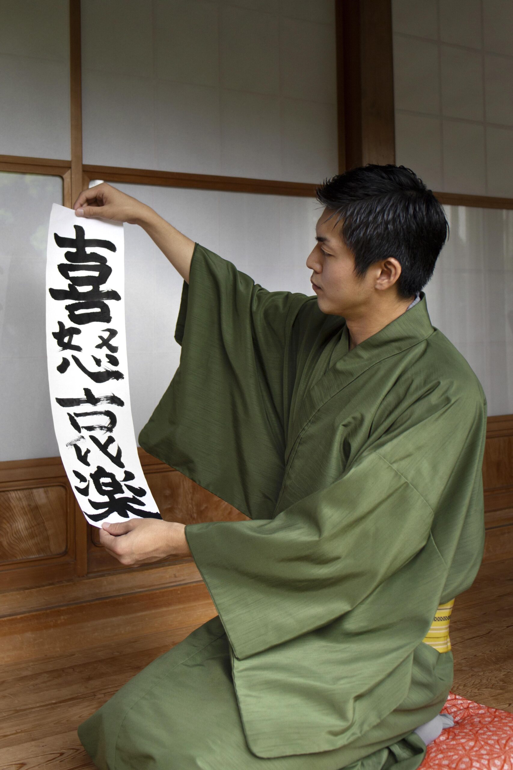 man-holding-paper-with-japanese-handwriting