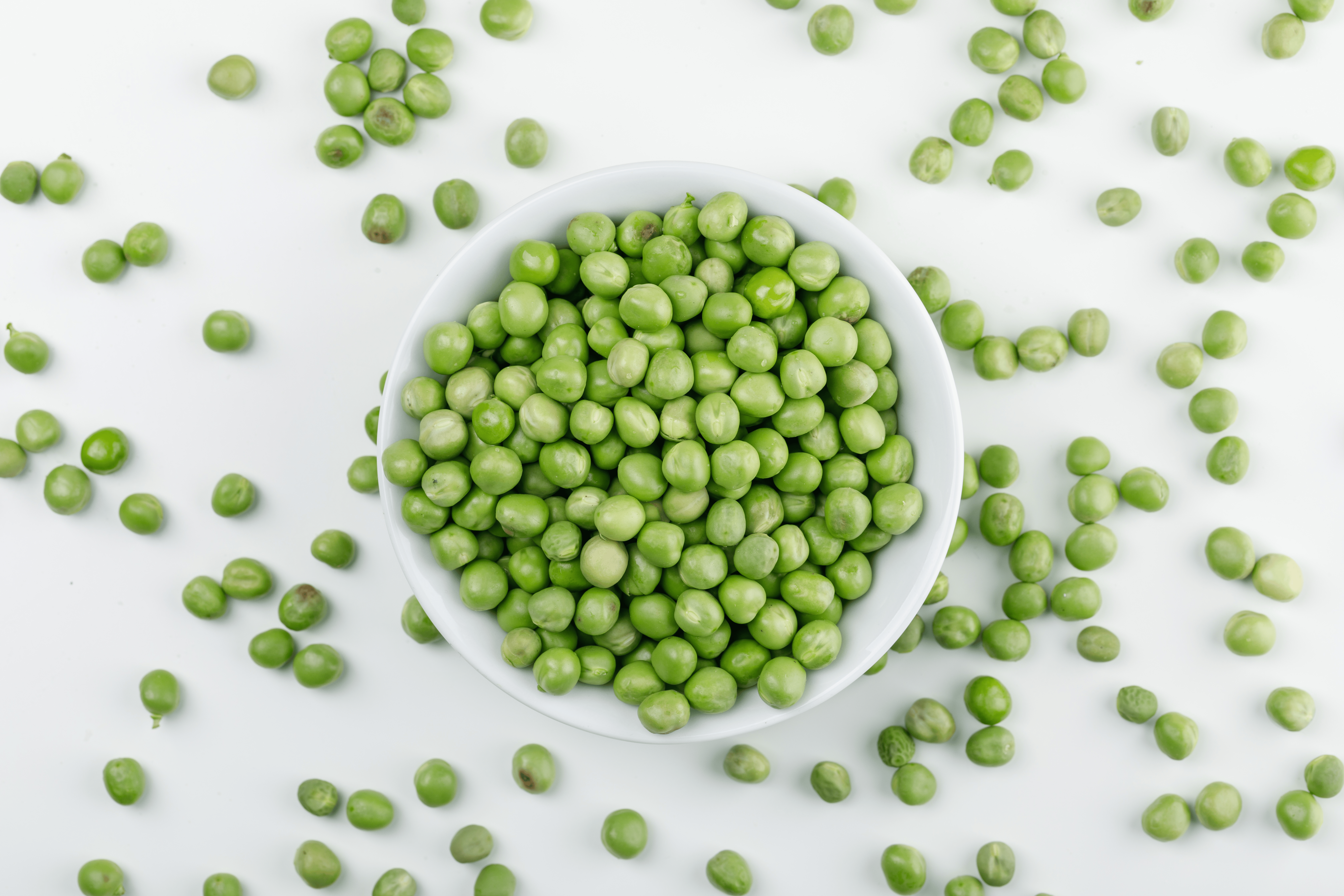 peas-white-bowl-top-view-white-wall